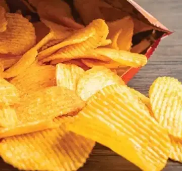 Market rafında salam ve cips ambalajının içindekiler listesine bakılan yakın çekim