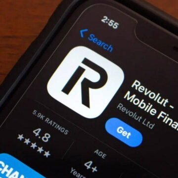 Revolut, çoklu para birimi destekli kart ve mobil uygulama ile dijital bankacılık hizmeti sunuyor. Akıllı telefonda açık Revolut uygulaması ve yanında duran çoklu para birimi destekli kart